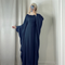 Person wearing a navy blue abaya and beige hijab against a white curtain background