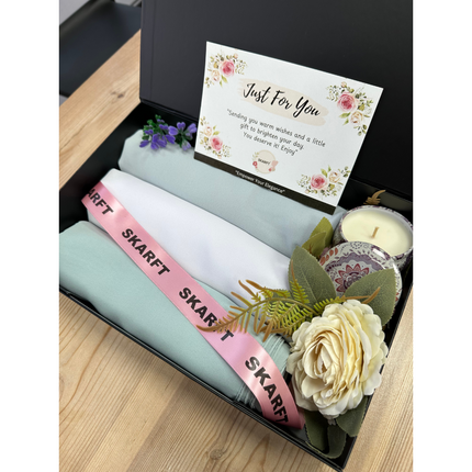 Hijabs in a box with scented candle, greeting card and flowers.