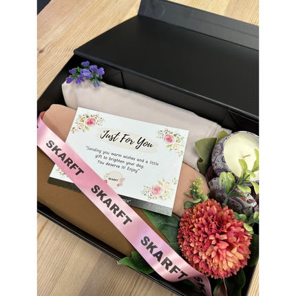 3 Hijabs in a black box on a table with scented candle and flowers