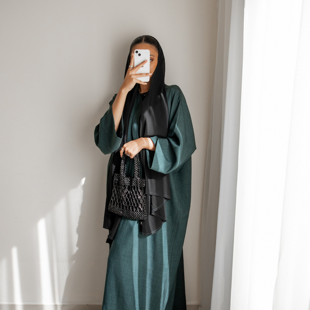 women wearing a green abaya and black hijab scarf